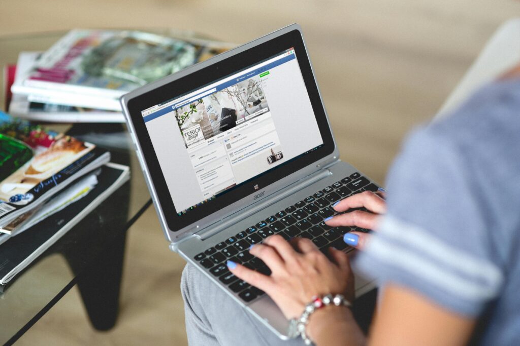 A woman typing on a laptop with social media on the screen, indoors FACEBOOK
